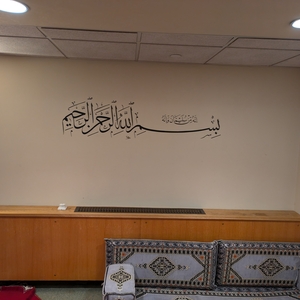 The Musalla at Yale, with a low couch underneath a wall with arabic script.