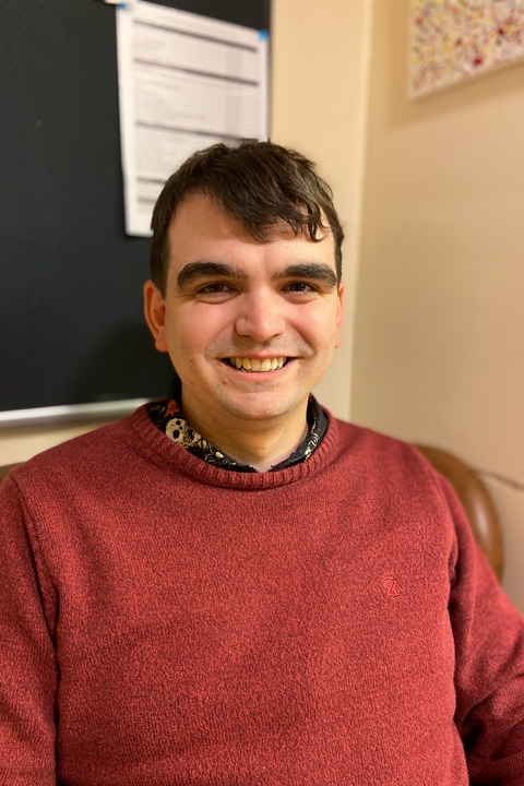 Ben Crome, a white man with short dark brown hair, smiling towards the camera