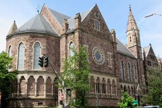 Exterior of Battell Chapel, a high Victorian Gothic church, with a visibler ose window and spire.