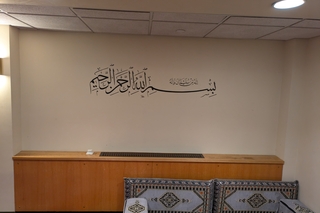 The Musalla at Yale, with a low couch underneath a wall with arabic script.