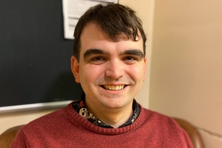Ben Crome, a white man with short dark brown hair, smiling towards the camera