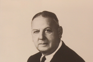 A black and white posed portrait photo of Sidney Lovett, a white man with short hair in a suit.