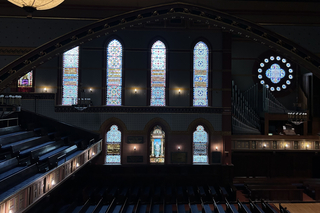 A wide shot of the stained glass one side of Battell Chapel, including the Rose Window above the organ.