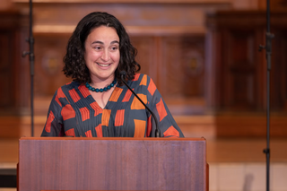 Maytal Saltiel laughing while standing behind a podium