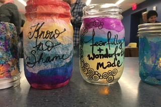 A closeup of two glass jars that have been colored, with text reading 'know no shame' and 'fearfully and wonderfully made'.