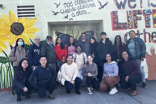 A group of students posed in front of a wall with a graffiti mural