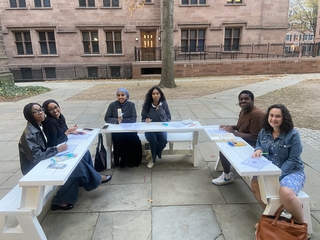 A group of people coloring on fold down benches in the old campus courtyard.