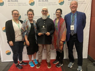 Some of the Yale chaplains on a red carpet against a backdrop saying 'ACSLHE'.