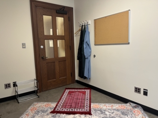 A small white room with a prayer rug on the floor.